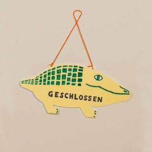 Stilisiertes Krokodil aus Pappe als Ladenschild zum Wenden, beschriftet mit "offen" und "geschlossen"
