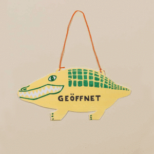 Animation eines stilisierten Krokodils aus Pappe als Ladenschild zum Wenden, beschriftet mit "offen" und "geschlossen"
