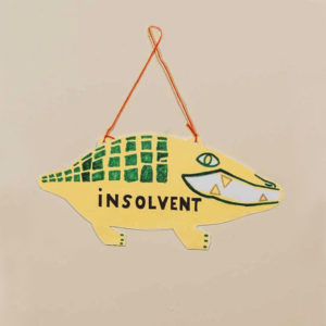 Stilisiertes Krokodil aus Pappe als Ladenschild zum Wenden, beschriftet mit "offen" und "insolvent"